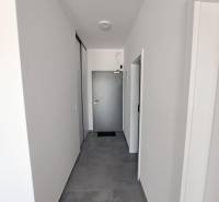 A corridor in commercial premises with white walls and tiles in neutral tones.