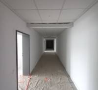 A narrow corridor in commercial premises with white walls and a makeshift floor.