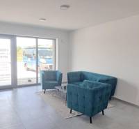 Commercial space with turquoise seating, gray flooring, and a large window.