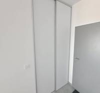 White sliding wardrobe in commercial premises with simple grey doors.