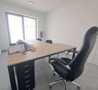 Office with a black chair, a desk with a wood finish, and a window in commercial premises.