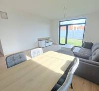 Dining room in a family house with a sofa and wood-patterned flooring.