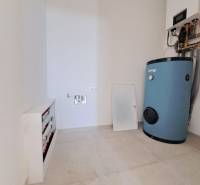 Boiler room in a family house with boilers and piping on a light-colored floor.