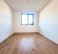 A view of a room with white walls and a wood-patterned floor in a family house.