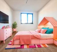 Bright children's room in a family house with pink furniture and a wooden decor floor.