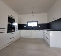 White kitchen unit and black tiles in a family house with a window and appliances.