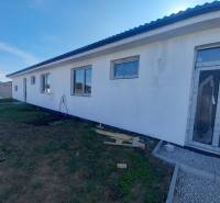 A family house in Galanta with a white facade, large windows, and an unfinished surrounding area.