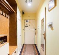 A hallway in a 3-room apartment with a coat rack, a mirror, and simple lighting.