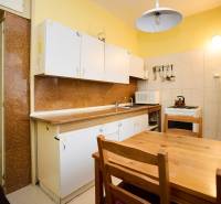 A kitchen with a wooden table in a three-room apartment. Cabinets, stove, refrigerator with magnets.