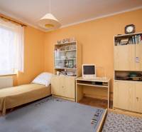 A room in a 3-room apartment with a bed, wardrobes, an old computer, and a lit lamp.