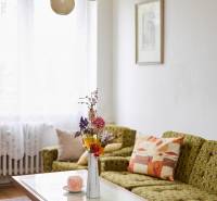A bright living room in a three-room apartment with a sofa, table, and decorative flowers in a vase.