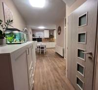 Interior of a family house with a kitchen, white furniture, and a wooden decor floor.