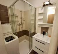 Bathroom in a 4-room apartment with a washing machine, shower, and sink with storage space.