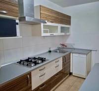 A kitchen in a 4-room apartment with a gas stove, extractor hood, and a wooden decor kitchen unit.