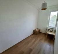 A room in a 4-room apartment with simple furniture and a wooden decor floor.