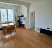 Dining room with a wooden table and chairs, floor with wooden decor in a 4-room apartment.