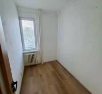 A small room with a wooden decor floor in a 4-room apartment, light from the window.