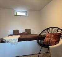 Bedroom in a family house with a simple bed and a comfortable armchair.