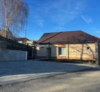 A family house in Blatné with a brown roof, a paved parking area, and a concrete fence.