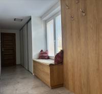 A hallway in a family house with coat hooks and seating with a cushion, floor with wood decor.