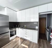 A kitchen with white cabinets and a wood-patterned floor in a studio apartment.