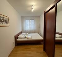 Bedroom with a bed, built-in wardrobe, and wooden decor flooring in a 3-room apartment.