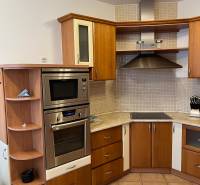 A kitchen in a 3-room apartment with a wooden decor floor and a corner countertop.