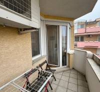 A balcony with furniture and a washing machine in a 3-room apartment.