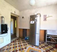 A kitchen in a family house with an older design, a refrigerator, and a tiled floor.