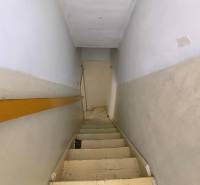 A narrow staircase in a family house with white walls and wooden railing.