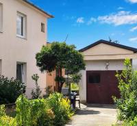 A family house in Partizánske with a garage surrounded by a garden full of green plants.