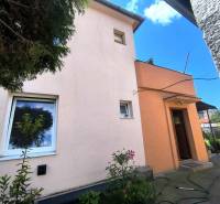 The family house in Partizánske has a pink facade, small windows, and an entrance door.