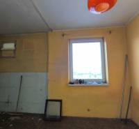 A room in a family house with a window, a broom, and orange lighting.