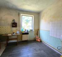 A kitchen in a family house with old furniture, scattered kitchen utensils, a window with a view.