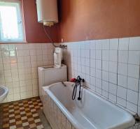 Bathroom in a family house with a bathtub and a water heating boiler.