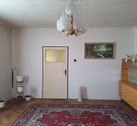 Living room in a family house with a carpet, chandelier, painting, and display cabinet.
