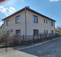 A family house in Tachtoch with plaster, next to the road and a metal fence.