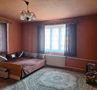 A room in a family house with a bed, carpet, curtains, and a nightstand.