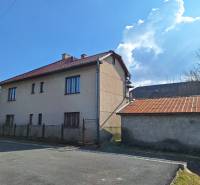 A family house in Tachtá with a red roof and a metal fence on the corner of the street.