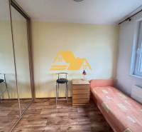 A room with a bed, a cabinet, and a floor with a wooden decor in a 3-room apartment.