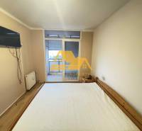 Bedroom in a 3-room apartment with a bed, a TV on the wall, and access to the balcony.