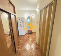 A hallway in a 3-room apartment with ceramic tiles, a built-in wardrobe, and a refrigerator in the background.