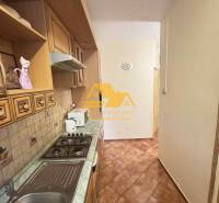 A narrow kitchen in a three-room apartment with a gas stove and ceramic tiles.