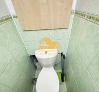 A toilet with green tiles and wooden paneling in a 3-room apartment.