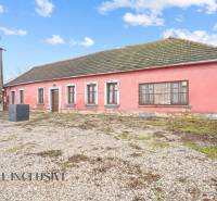 A family house in Šintava with a stone base, pink facade, and wooden windows.