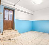 The interior of a family house with blue walls and a light floor next to wooden doors.