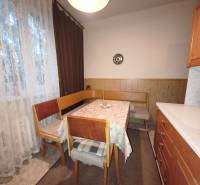 Dining area with a table and chairs in a 3-room apartment with a wooden decor floor.