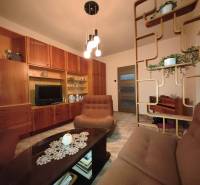 Living room in a 3-room apartment with wooden furniture and decorative shelves.