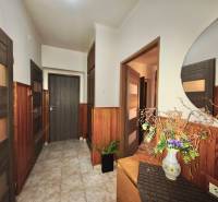 Flower decoration in the hallway of a 3-room apartment with wooden paneling and a mirror.