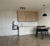 A kitchen in a 2-room apartment with a wooden decor floor and a dining table.